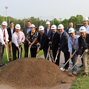  Representatives from OPCSD and others involved in the facilities project digging shovels into dirt.